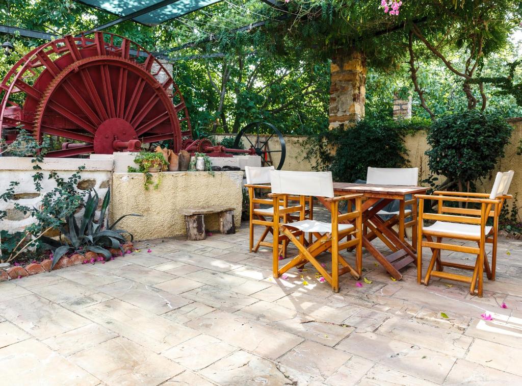 un patio con una mesa de madera, sillas y una rueda en Mansion Argyrakiko - 3 bedroom house in Kampos, en Chios