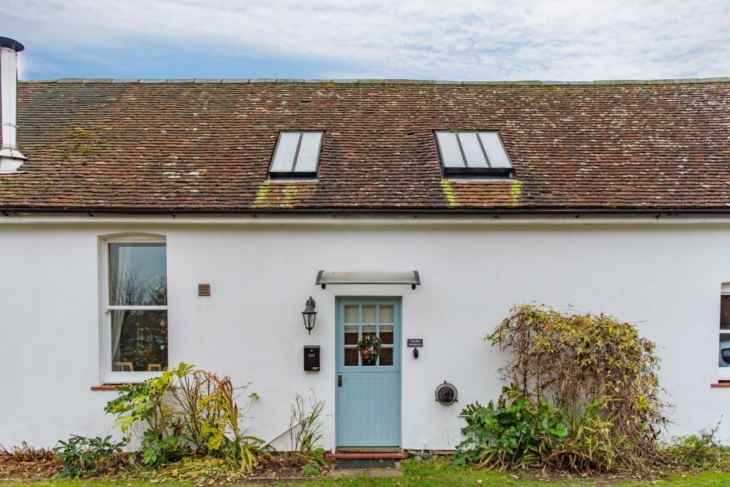 a white house with a blue door and windows at The Old Schoolroom by Bloom Stays in Canterbury