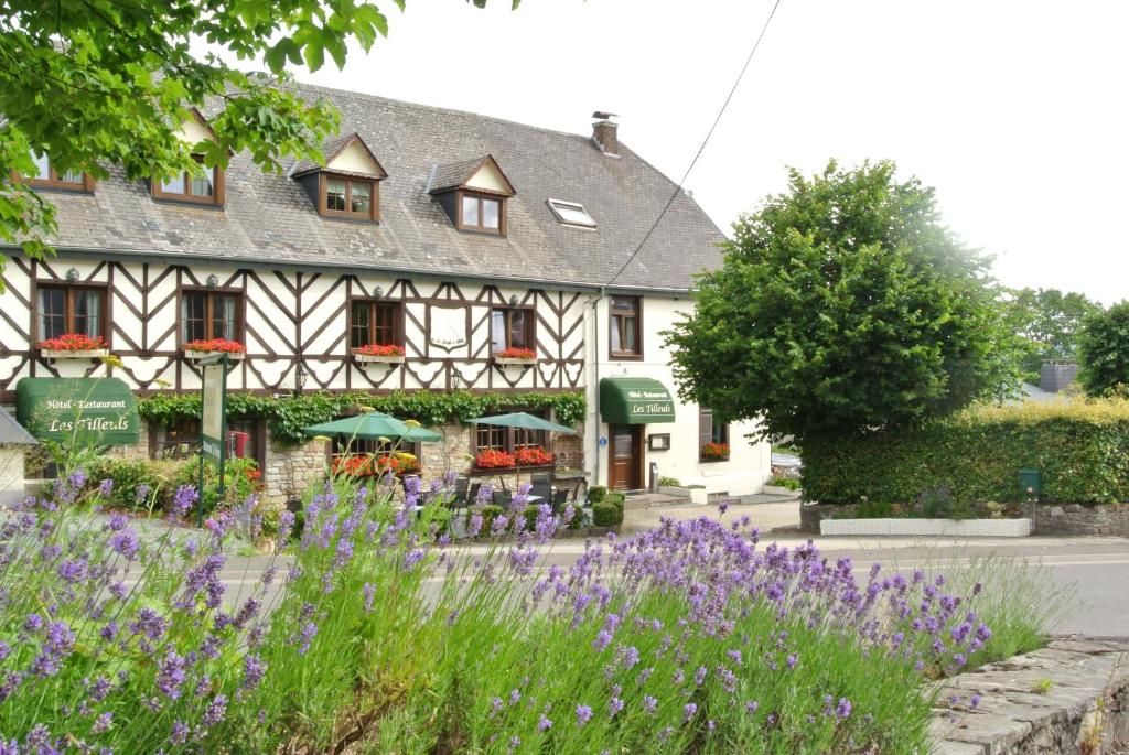 un bâtiment avec des fleurs violettes devant lui dans l'établissement Hostellerie des Tilleuls, à Smuid