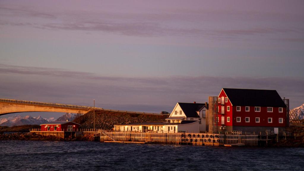 uma ponte sobre uma massa de água com casas e edifícios em Fast Hotel Henningsvær em Henningsvær