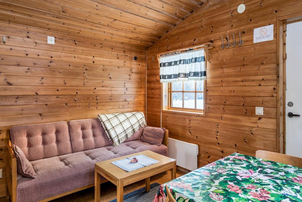 ein Wohnzimmer mit einem Sofa und einem Tisch in der Unterkunft Hyttgårdens stugby i Huså, Åre kommun in Huså