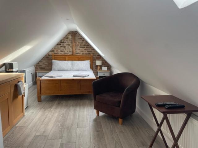 um quarto com uma cama e uma cadeira num sótão em The Attic Suite Selsey em Selsey
