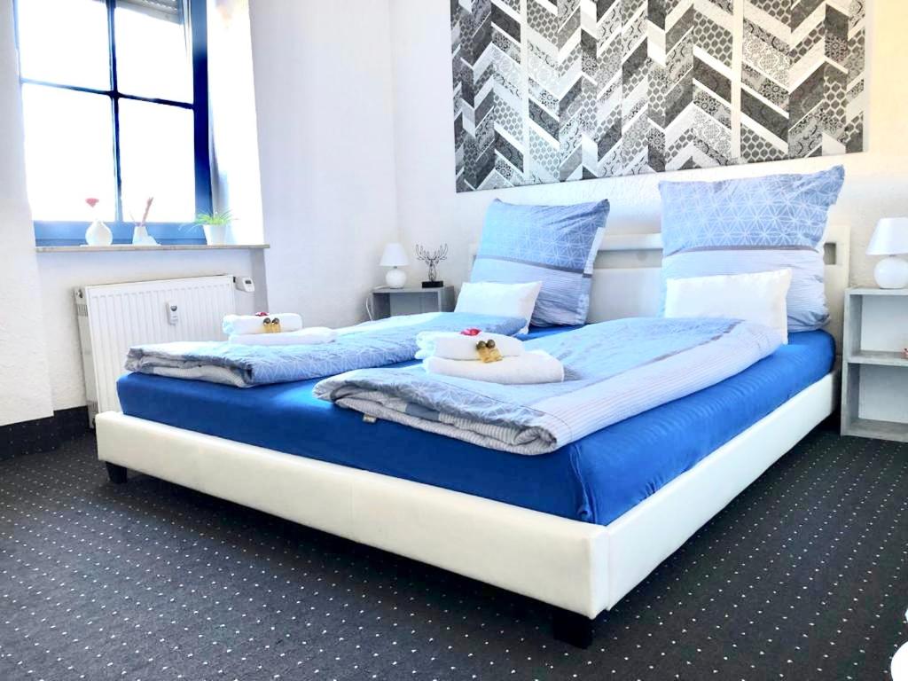 uma cama grande com lençóis e almofadas azuis e brancos em #WORLD Ferienwohnung Schkeuditz em Schkeuditz