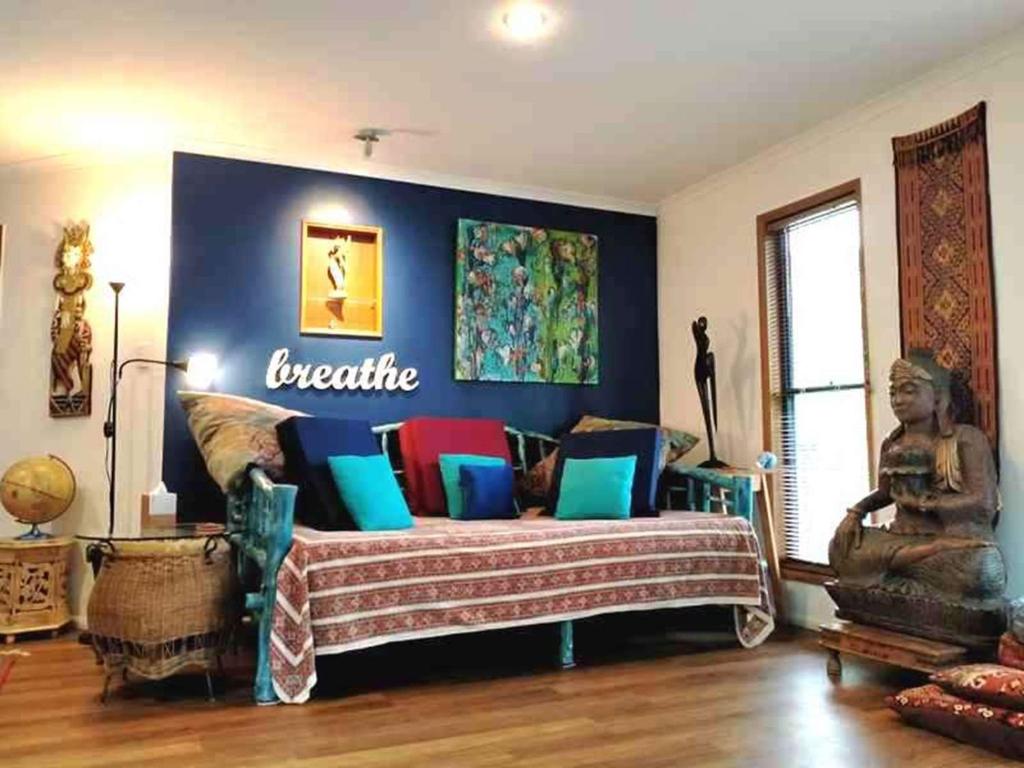 sala de estar con sofá y almohadas coloridas en Cosy Romantic Cottage, en Tallebudgera
