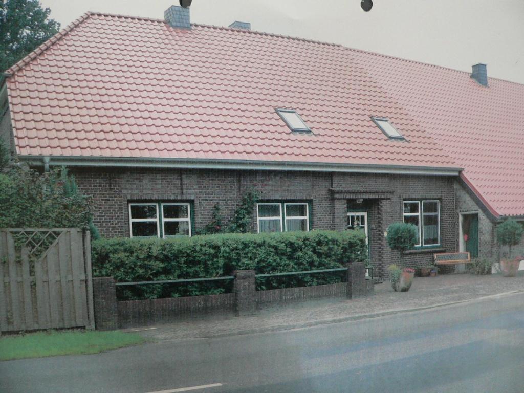 a brick house with a red roof on a street at Ferienwohnung Zum grünen Holz in Bohlenberge