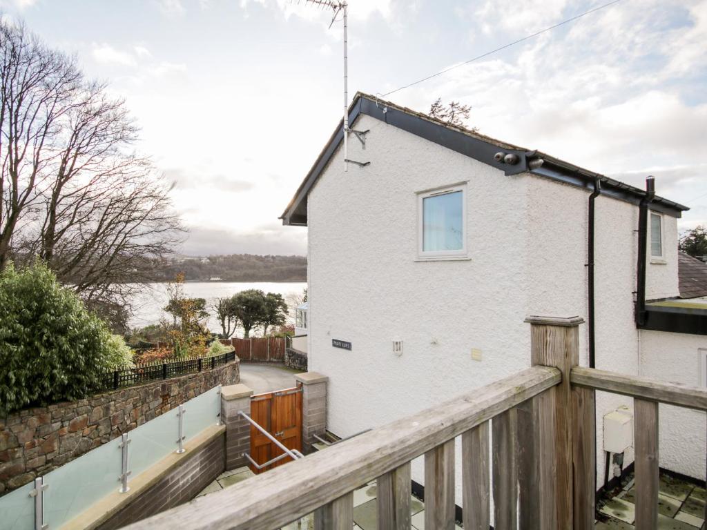 a white house with a wooden balcony with a fence at Pilots Loft in Menai Bridge