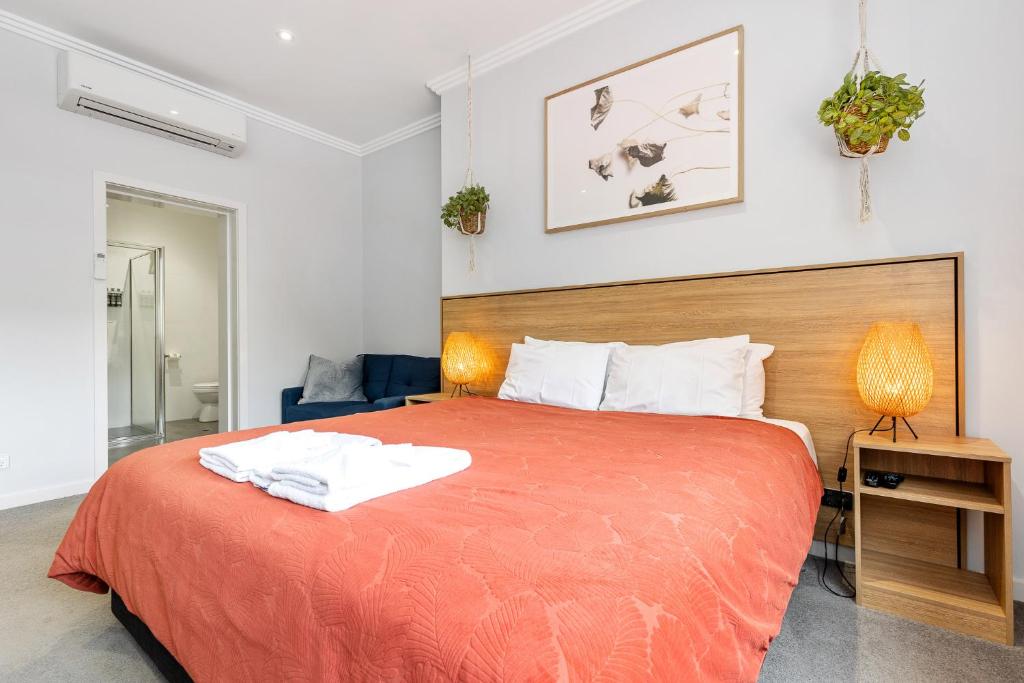 a bedroom with a large bed with an orange blanket at Civic Apartments in Wagga Wagga