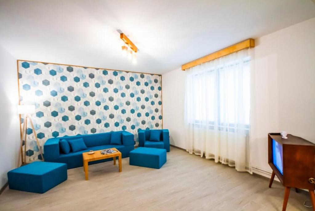 a living room with a blue couch and a tv at Apartament Aretta in Braşov