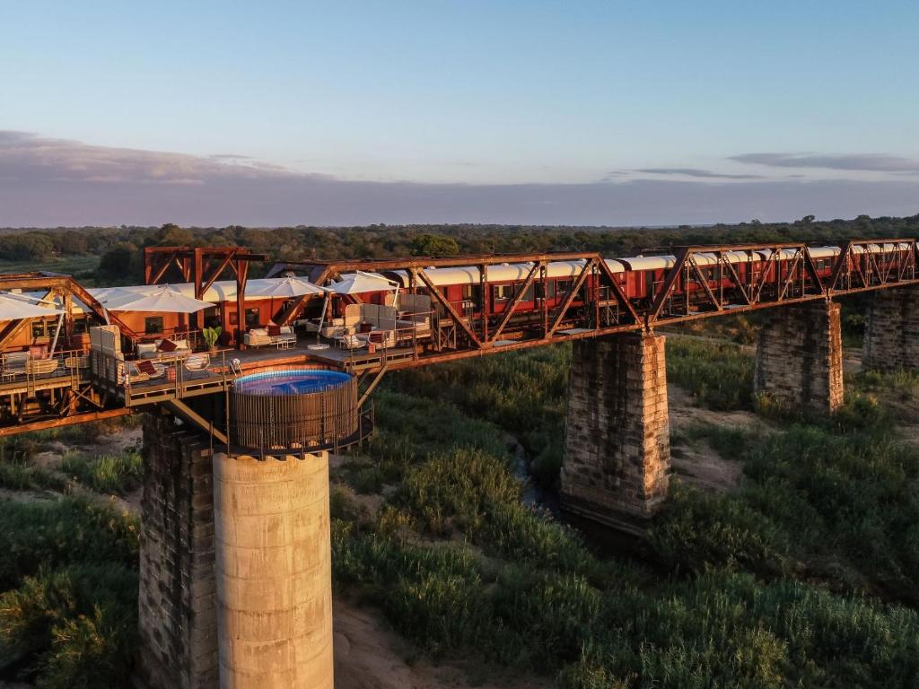 a train crossing a bridge with a train on it at Kruger Shalati - Train on The Bridge & Garden Suites in Skukuza