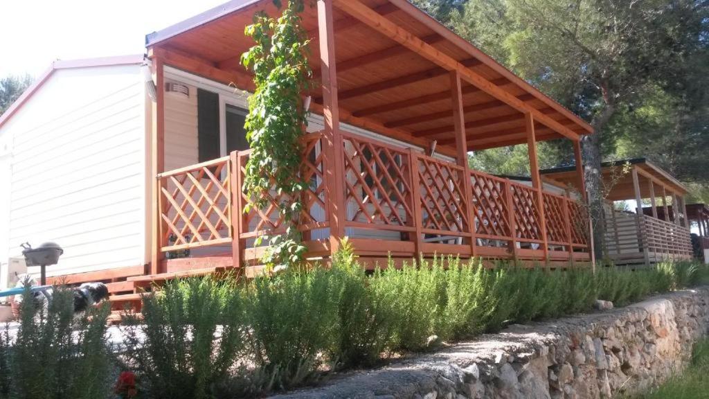 a cabin with a large deck on the side of it at Mobile home Sea Jezera Village, otok Murter in Tisno