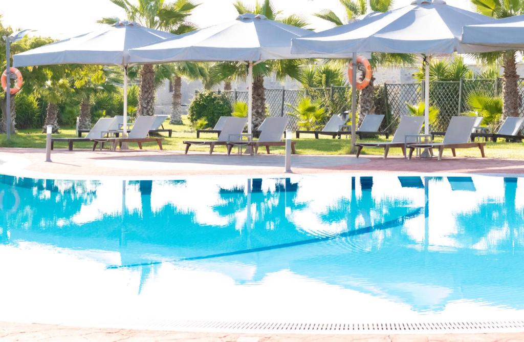 a swimming pool with chairs and umbrellas next to a pool at Aktaion Resort in Gythio