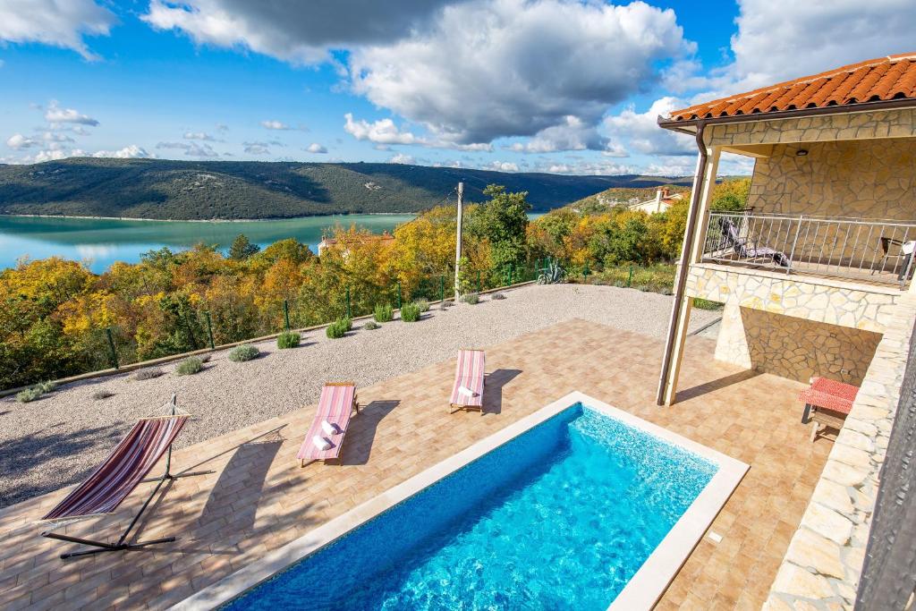 uma piscina com cadeiras e vista para um lago em Villa Valente with Pool em Labin