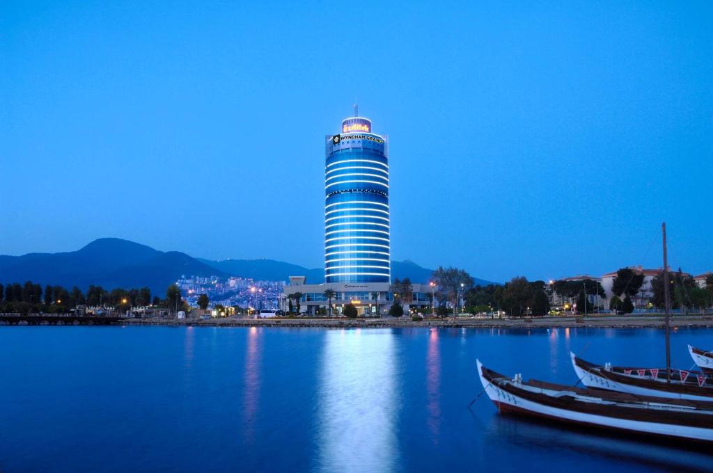 a tall building with two boats in the water at Wyndham Grand İzmir Özdilek in İzmir