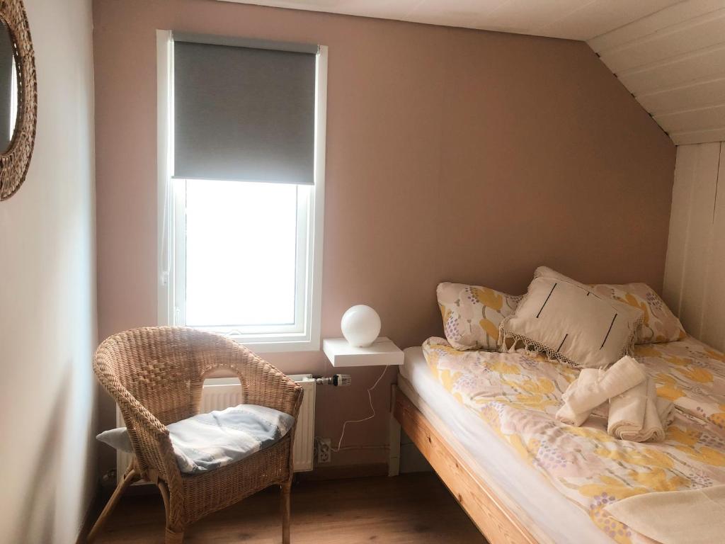 a bedroom with a bed and a chair and a window at Bard Cottage in Akranes
