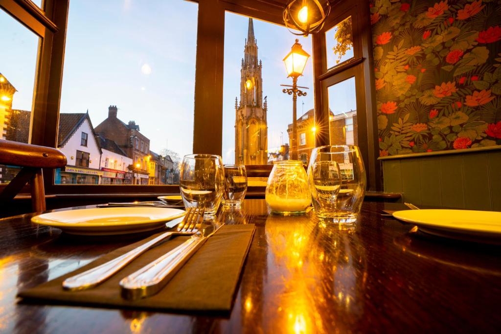 una mesa de madera con vasos y utensilios en un restaurante en The Crown Hotel en Glastonbury