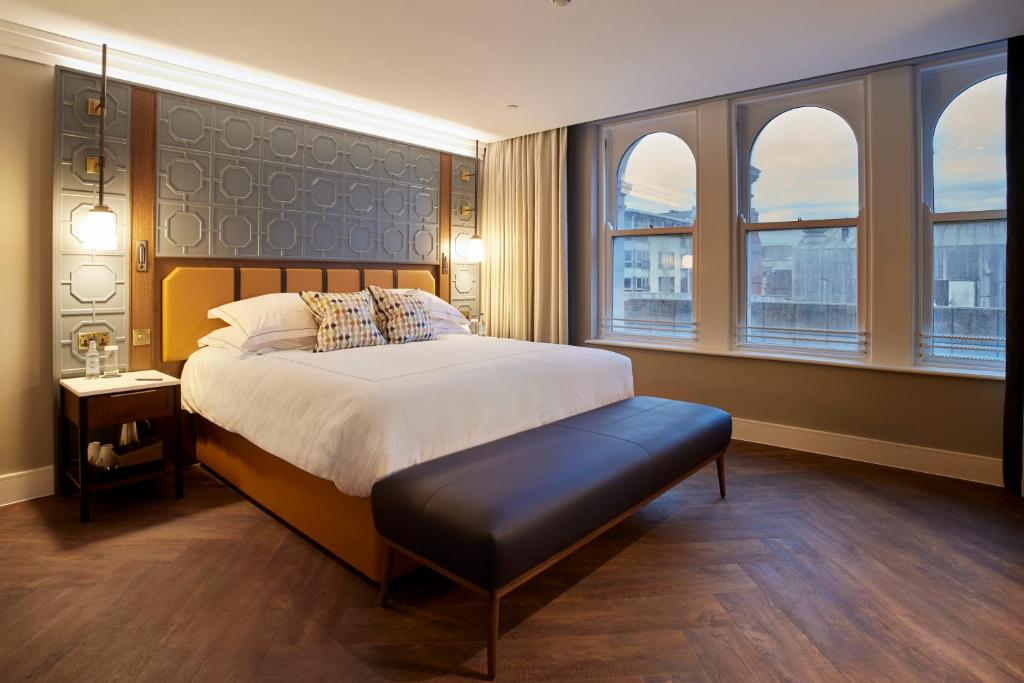 a bedroom with a large bed and two windows at The Parkgate Hotel in Cardiff
