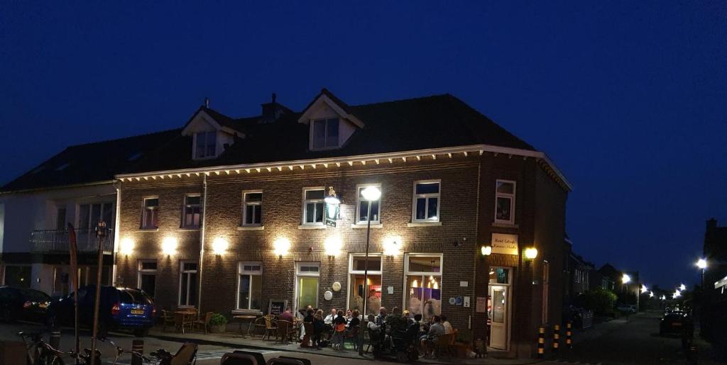 un groupe de personnes debout à l'extérieur d'un bâtiment la nuit dans l'établissement Hotel-Cafe Knoors-Meeks Stein Urmond, à Berg