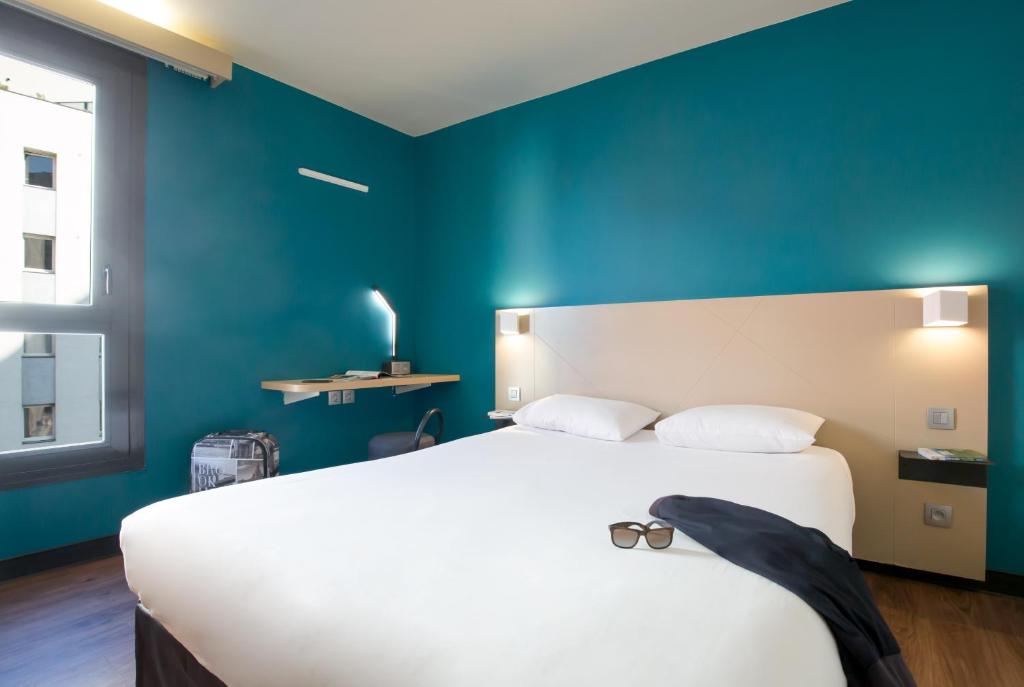 - une chambre avec un grand lit blanc et un mur bleu dans l'établissement B&B HOTEL Marseille Centre La Timone, à Marseille