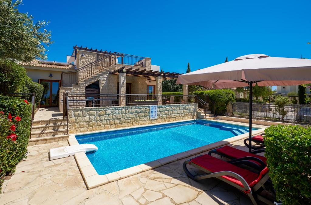 a swimming pool with two chairs and an umbrella at 3 bedroom Villa Madelini with private pool, Aphrodite Hills Resort in Kouklia