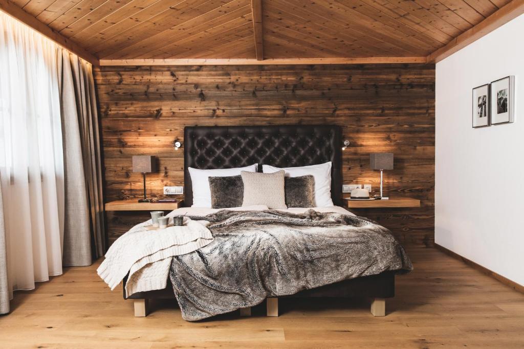 a bedroom with a bed with a wooden wall at Alpines Gourmet Hotel Montanara in Flachau