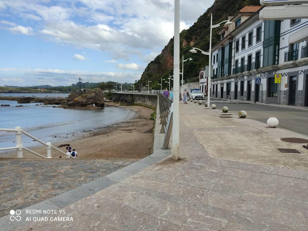 un niño sentado en la arena en una playa en Apartamentos Astilleros en Candás