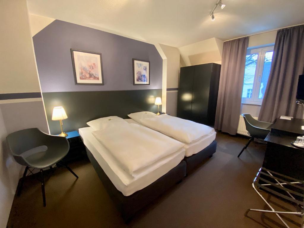 a hotel room with a large bed and a desk at Hotel Kaiserswerth in Düsseldorf