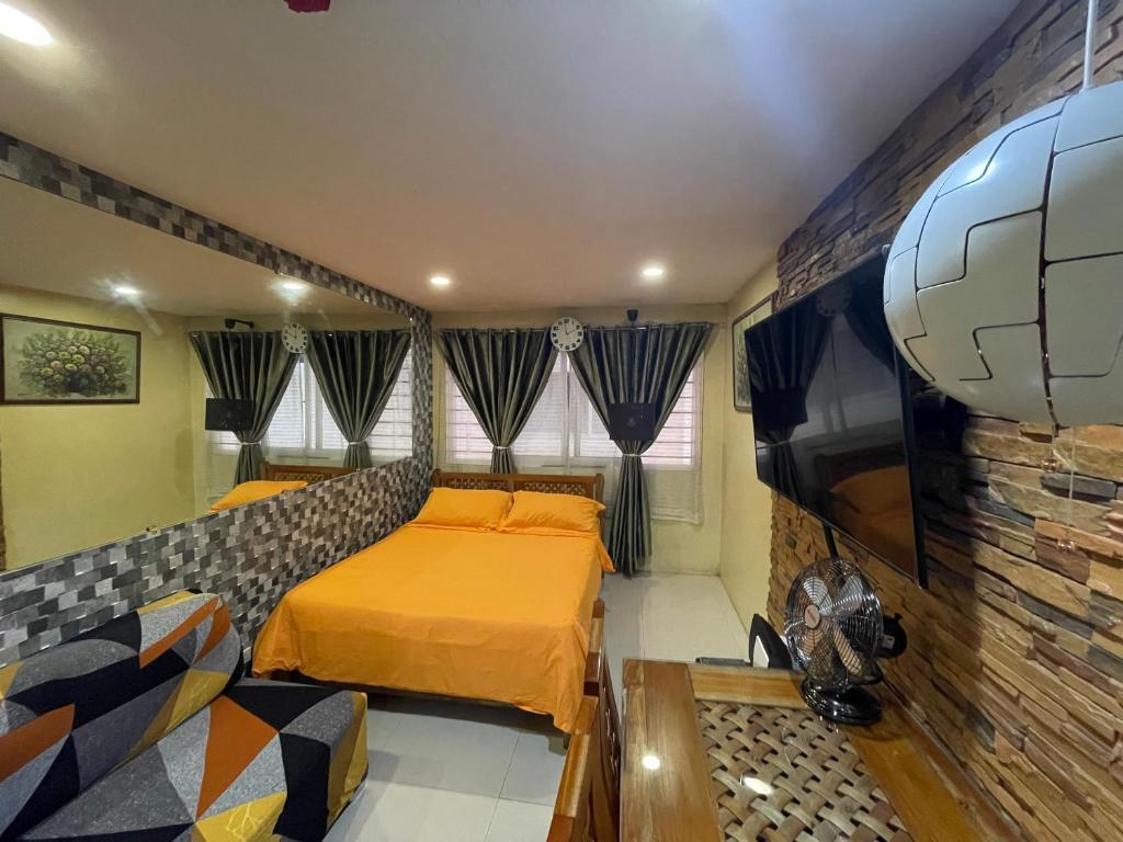 a bedroom with a bed and a couch and a tv at Cozy Studio Hotel-like Condominium at Megatower Residences in Baguio