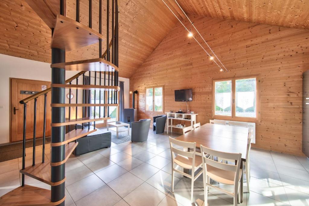 a dining room with a table and a wooden ceiling at Chalet de charme - Le Martinet in Ney