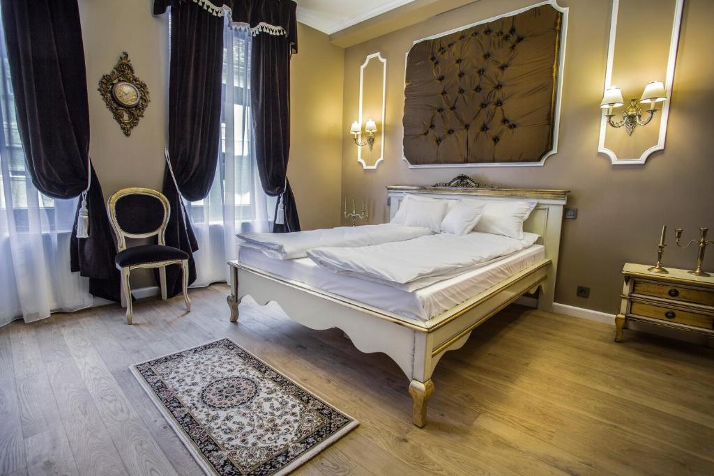a bedroom with a white bed and a chair at Casa Timpuri Vechi in Sibiu
