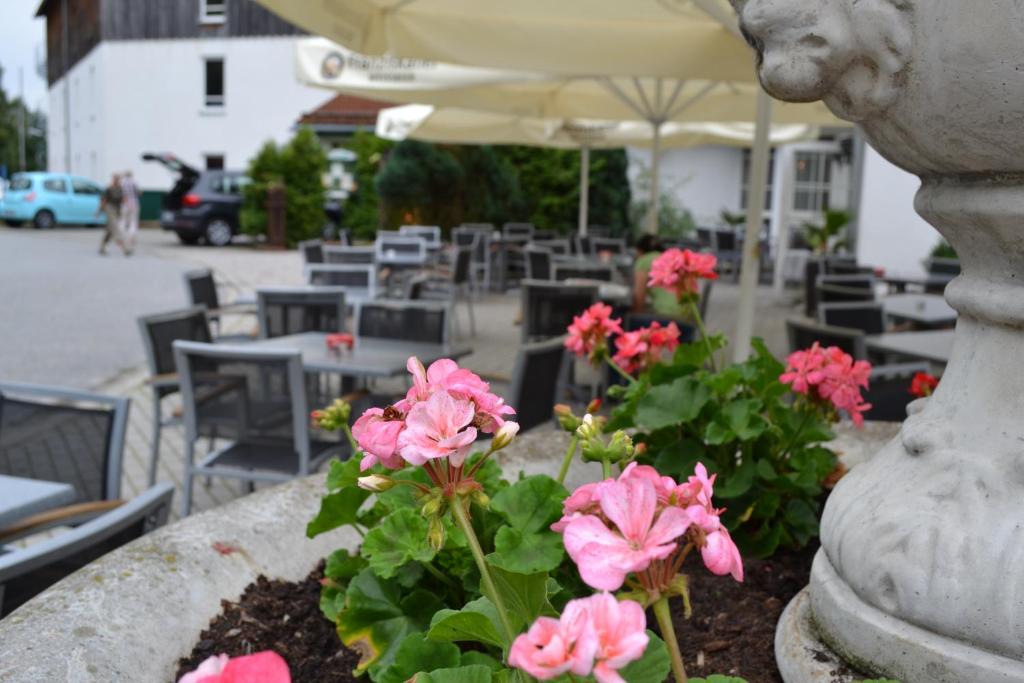 a planter with pink flowers and tables and chairs at Hotel am Pfahl in Viechtach