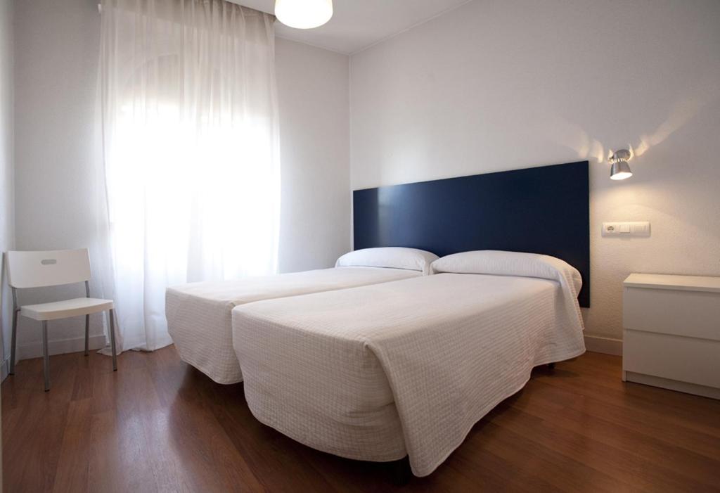 sypialnia z dużym białym łóżkiem i oknem w obiekcie Hostal Santa Isabel w Madrycie