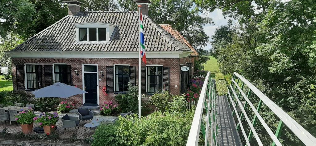a brick house with a flag on a deck at B&b Hoogholtje in Onderdendam