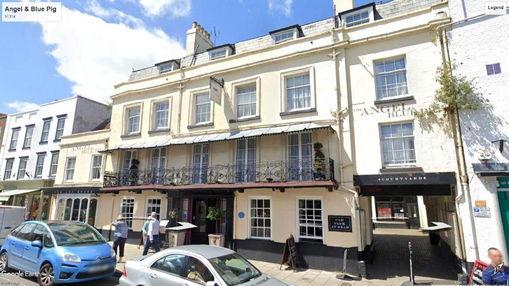 un gran edificio blanco con coches estacionados frente a él en The Angel & Blue Pig en Lymington