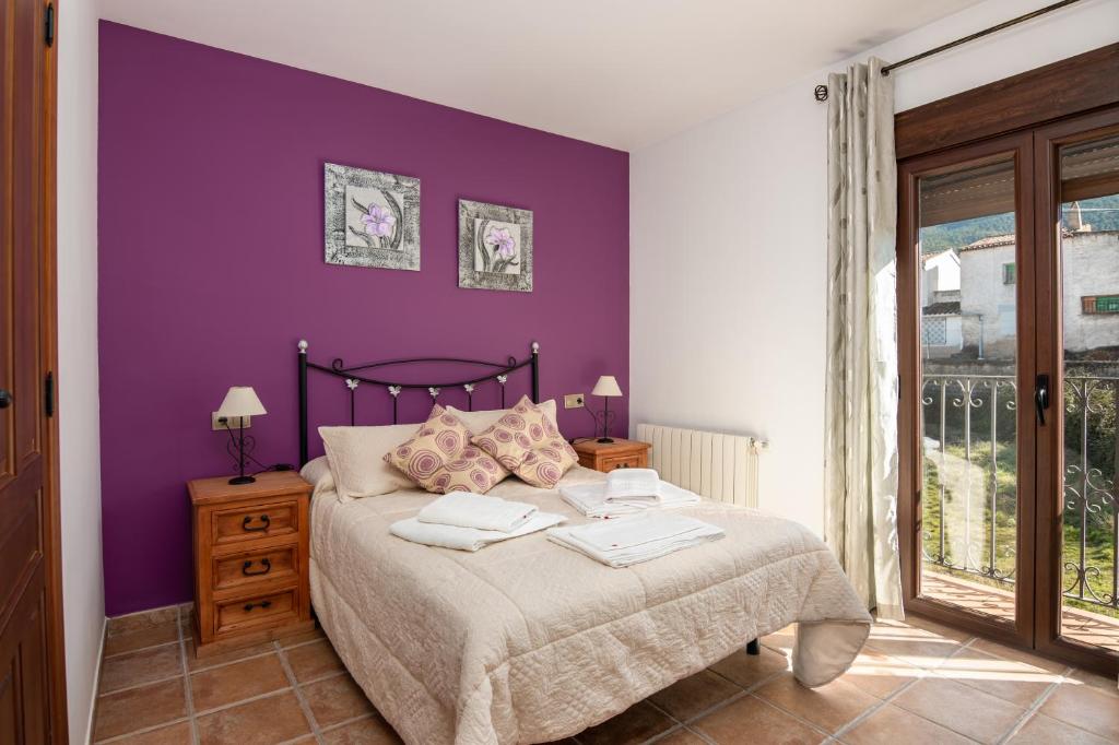 um quarto roxo com uma cama com duas toalhas em Mirador de El Yelmo em El Ojuelo