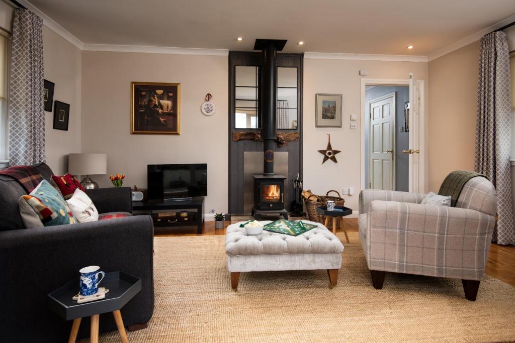 ein Wohnzimmer mit einem Sofa, Stühlen und einem TV in der Unterkunft Bastle Retreats Farm Cottage in Duns