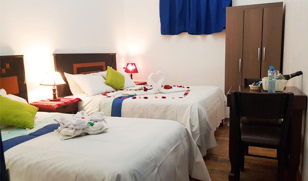 1 dormitorio con 2 camas y 1 silla en Hostal Tunupa, en Cusco