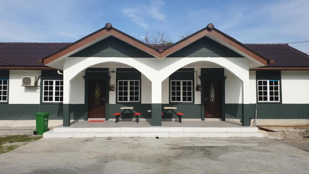 un bâtiment blanc et vert avec deux tables devant lui dans l'établissement MRI Residence 4 Bedroom Bungalow with Private Pool in Sg Buloh - No Pork & No Alcohol, à Merbau Sempak