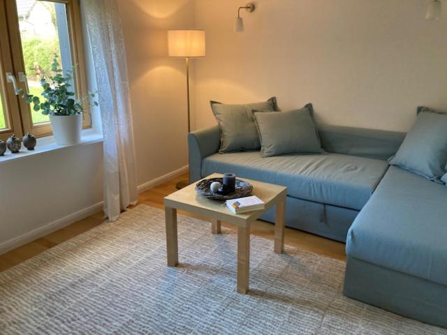 a living room with a blue couch and a table at Kleines Haus im Grünen in Hamburg