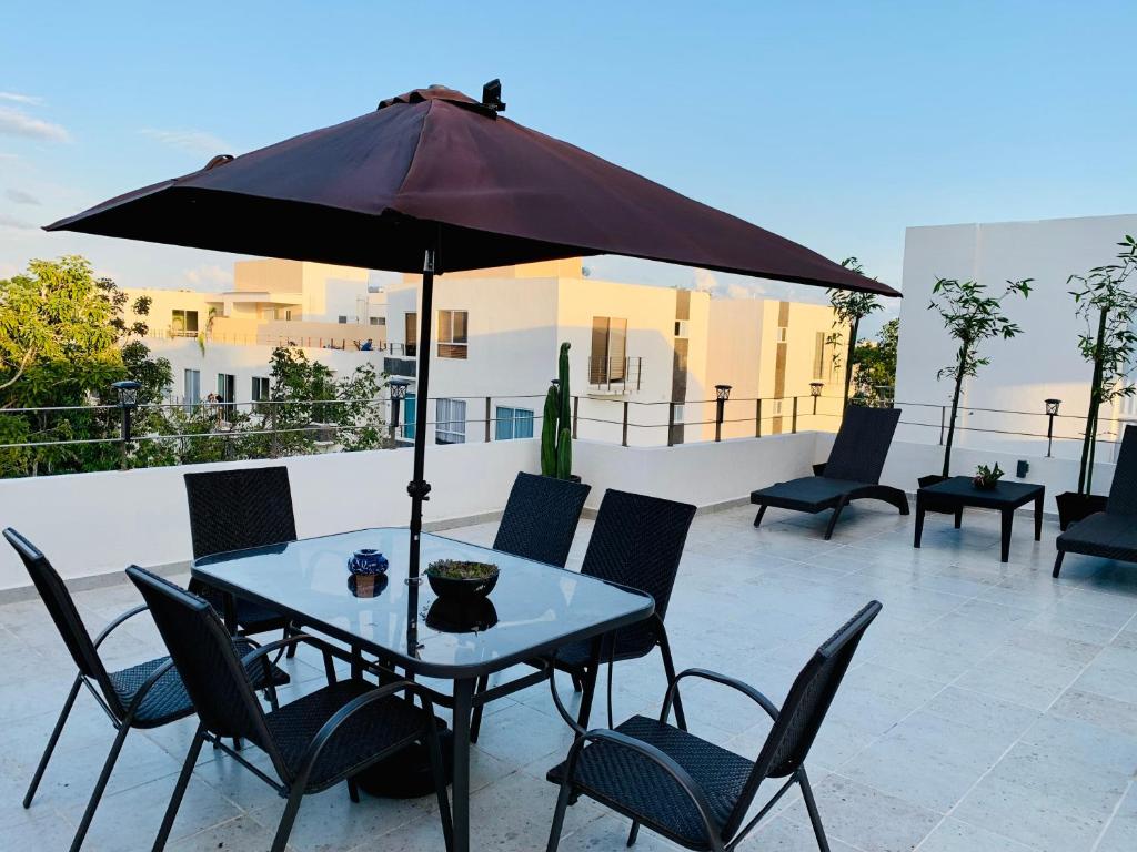una mesa y sillas con una sombrilla en el patio en Franks House Luxury Apartment "Shared House", en Cancún
