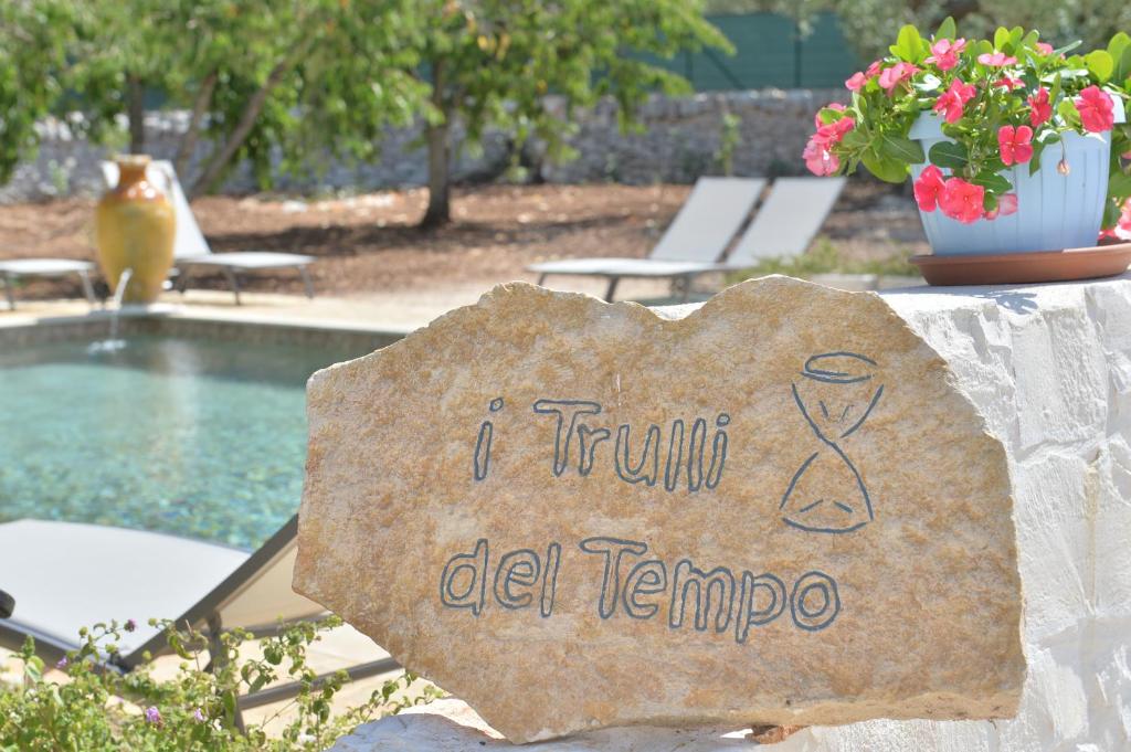een bord met de tekst "i trauma del tempo" naast een zwembad bij I Trulli del Tempo in Martina Franca