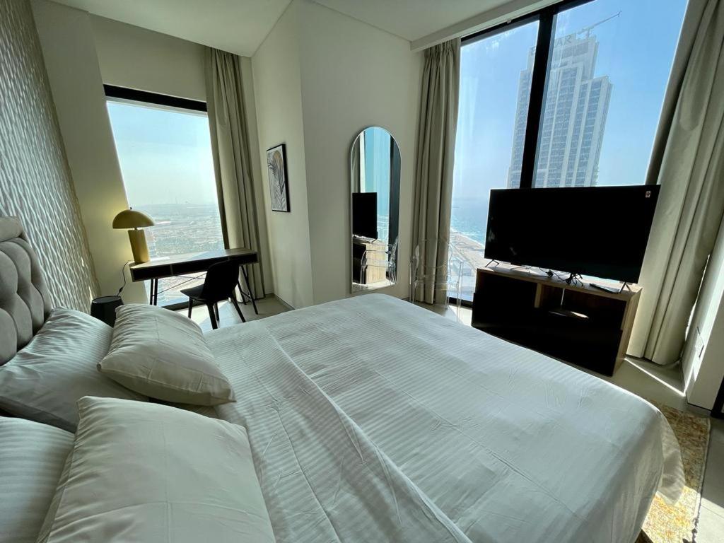 a bedroom with a large bed and a flat screen tv at LHG ADDRESS BEACH Residence in Dubai