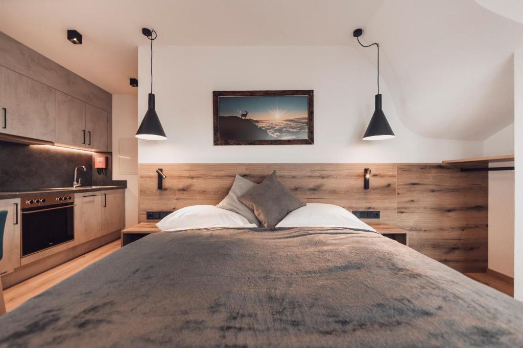 a bedroom with a large bed and two pendant lights at Alpenheim Apartment Ischgl in Ischgl