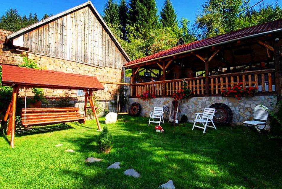 a yard with chairs and a house with a barn at Cabana Vânătorilor in Poiana Mărului