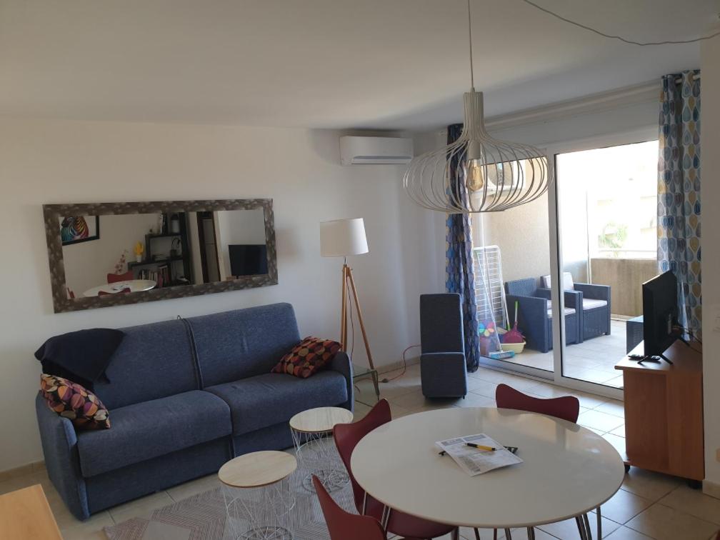 聖露西亞迪莫耶尼的住宿－Appartement T2 Bord de Mer - Maria Beach，客厅配有蓝色的沙发和桌子