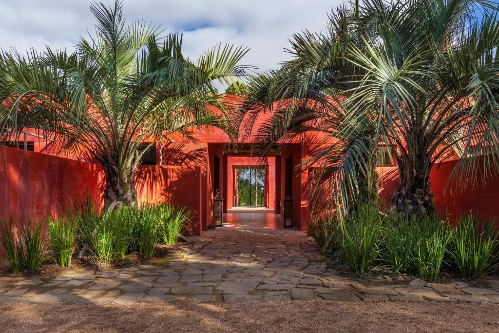 a red house with palm trees in front of a door at LUZ Culinary Wine Lodge in José Ignacio