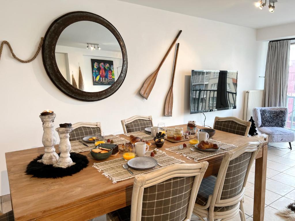 een eetkamer met een tafel en een spiegel bij Au travers du Hublot in Knokke-Heist