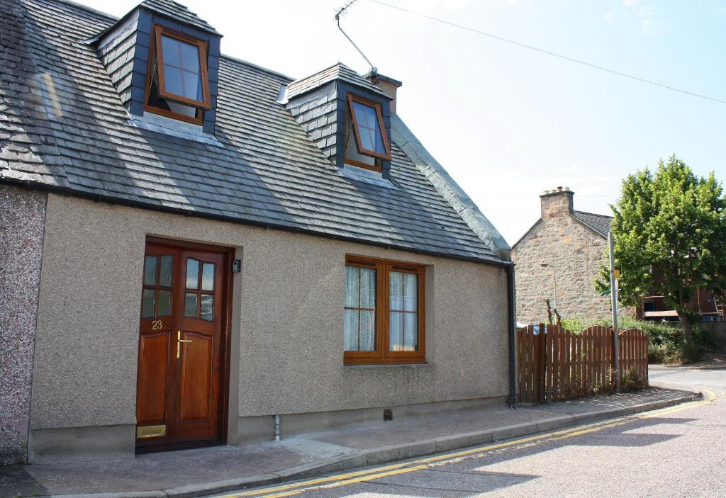 una casa con una puerta marrón y ventanas en una calle en 23 Fairfield, en Inverness