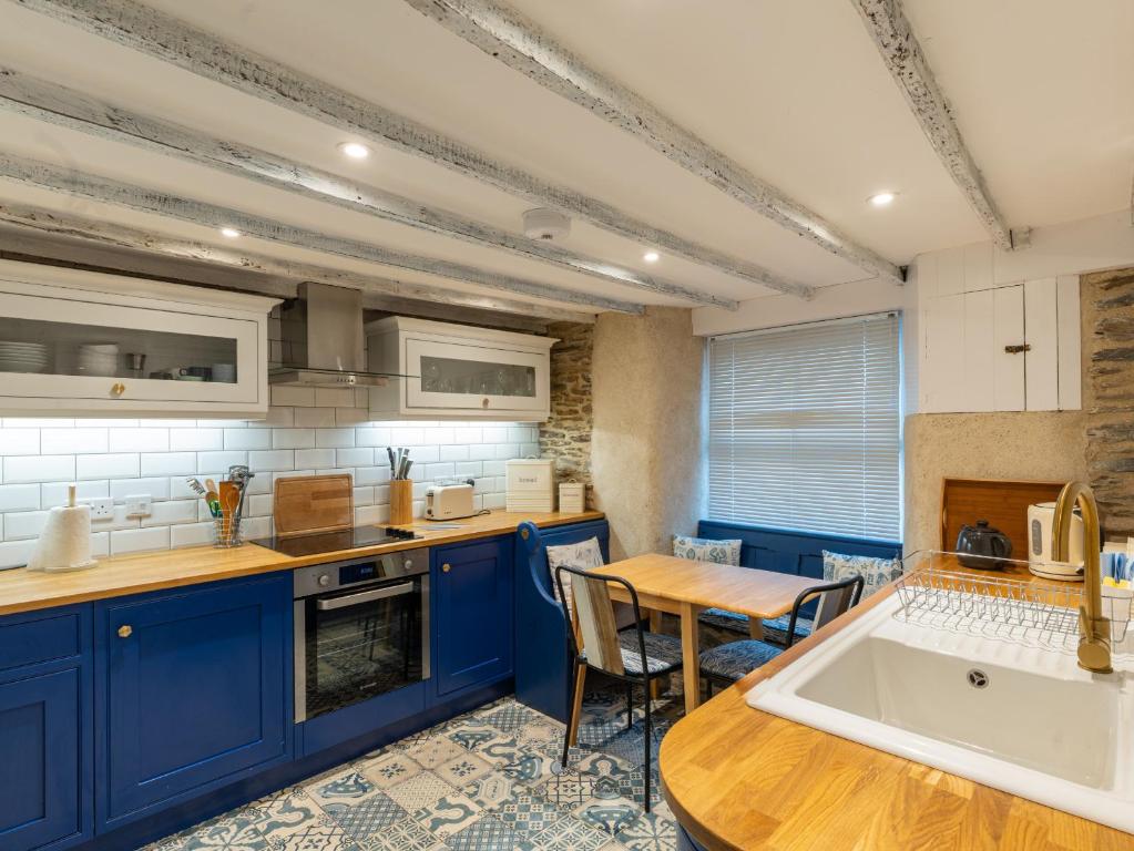 una cucina con armadi blu e tavolo in legno di Finest Retreats - Old Harbour Cottage a Mevagissey
