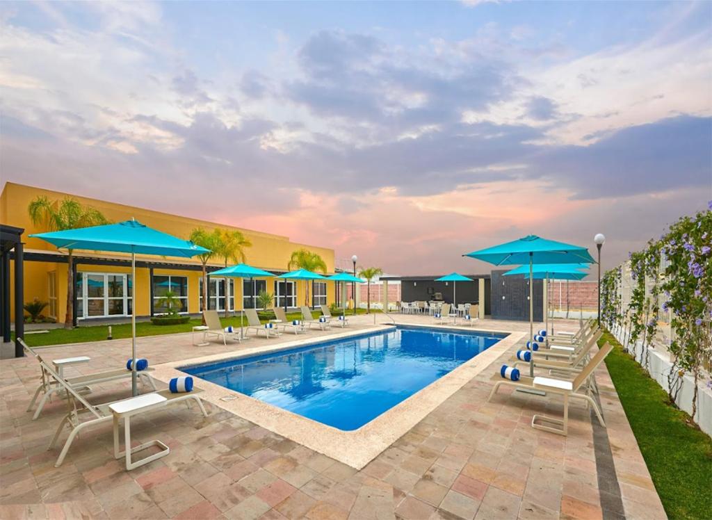 een zwembad in een hotel met stoelen en parasols bij Hotel Best Place Express in Zamora de Hidalgo