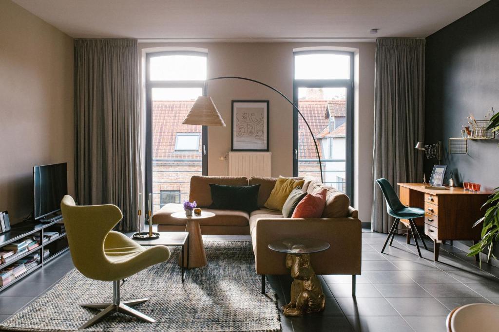 sala de estar con sofá y sillas en Hoeve de Reetjens - Le Marie, en Bilzen